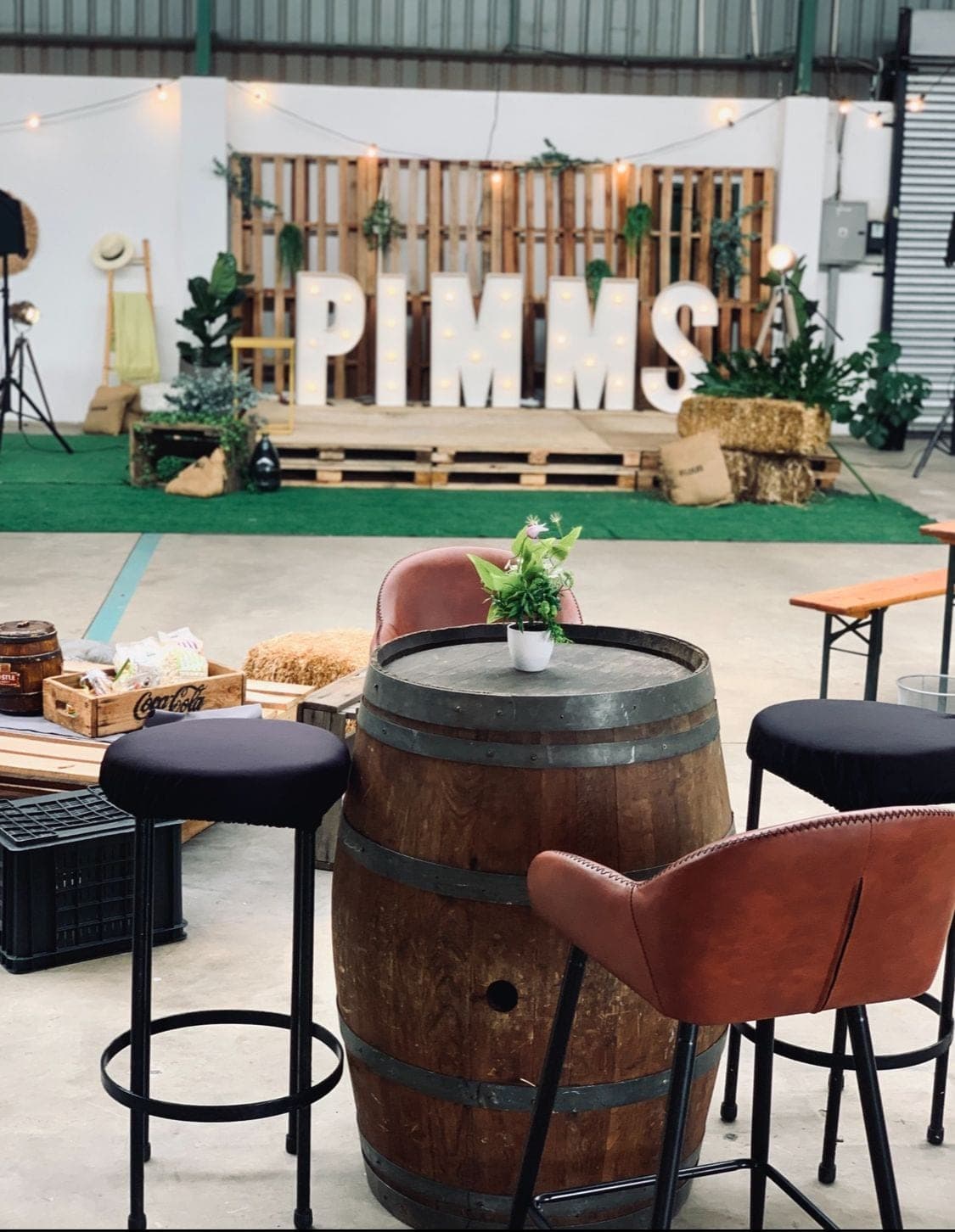 Rustic corporate activation with wine-barrel cocktail tables and marquee lettering
