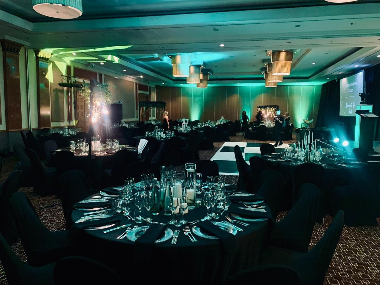 Dramatic corporate awards banquet with teal uplighting and full tablescape styling